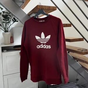 Adidas sweatshirt - En snygg mörkröd/vinröd sweatshirt som passar till det mesta. Tröjan är sprillans ny så skicket är 10/10. 