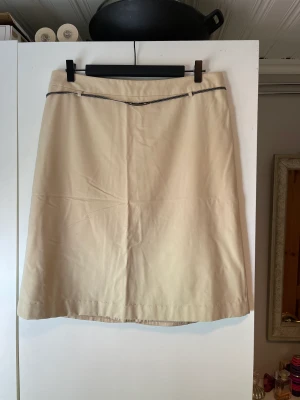 Kjol - En beige kjol med bälte. Storlek: 42.