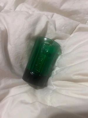 Jägermeister shotglas i glas - Säljer ett Jägermeister shotglas i glas med måttmarkeringar för 2cl, 4cl och 6cl. Glaset har en liten hällpip och är perfekt för att mäta upp shots eller drinkar. Snygg och enkel design som passar till festen eller hemmabaren. Har aldrig använt.