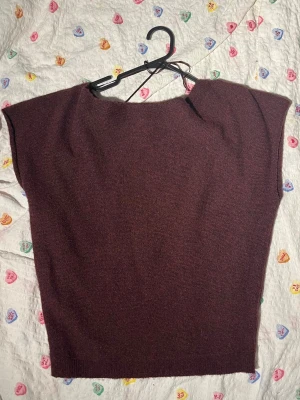 Vinröd stickad topp från Nelly - Säljer en vinröd stickad topp från Nelly. Modellen har korta ärmar, rak passform och bred halsringning. Materialet är mjukt och lätt, perfekt för lager på lager eller som den är. Enkel och stilren design som passar till mycket.