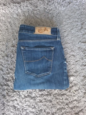 Jacob cohën jocelyn slim modell - Säljer ett par klassiska blå jeans med smal passform och snygg bakficka. Jeansen har normalhög midja, fem fickor och stängs med knapp och dragkedja. Materialet är mjukt denim som sitter skönt hela dagen.