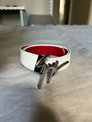 Giuseppe Zanotti - Snyggt vitt skärp med en unik silverfärgad spänne i form av en signatur. Insidan är röd vilket ger en cool kontrast. Perfekt accessoar för att lyfta din outfit.