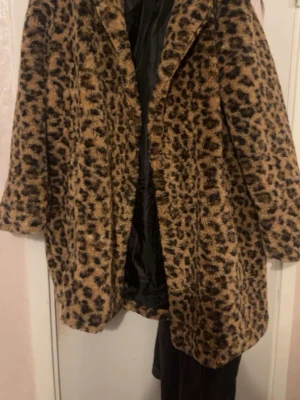 Leopardmönstrad pälsjacka - Snygg pälsjacka med leopardmönster i bruna och svarta toner. Jackan har en rak passform, bred krage och knäppning framtill. Fodrad med svart tyg på insidan. Perfekt statement-plagg för dig som vill sticka ut.