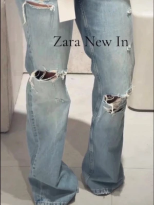 Ljusblå wide leg jeans med revor - Helt nya med prislapp Trendiga ljusblå jeans från Zara med wide leg-passform och låg midja. Jeansen har stora slitningar och revor på både lår och knän för en avslappnad och edgy look. Tillverkade i klassisk denim med en skön, lös siluett.