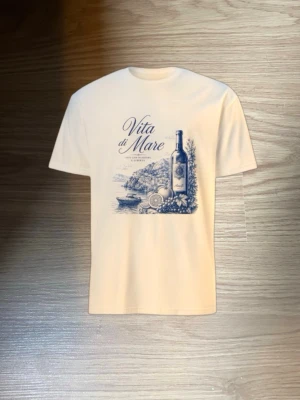Vit t-shirt med blått Amalfi-tryck - Snygg vit t-shirt med ett detaljerat blått tryck av en vinflaska, citroner och Amalfi-kustens landskap. Texten 'Vita di Mare' ger en italiensk vibe. Perfekt för dig som gillar stilrena motiv och vill sticka ut lite extra. Tveka inte att höra av er vid frågor 🤩