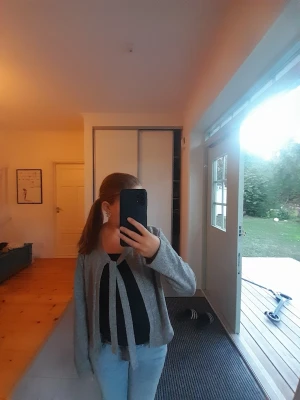 Grå kofta med knytband - Säljer en snygg grå kofta med långa ärmar och knytband framtill. Koftan har en avslappnad passform och är perfekt att slänga över en topp. Passar till jeans eller kjol för en chill look.