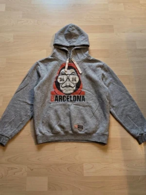 Grå hoodie med Barcelona-tryck - Grå hoodie med tryck på. Köpt i Spanien, kostade 500 kr. Knappt använd💕