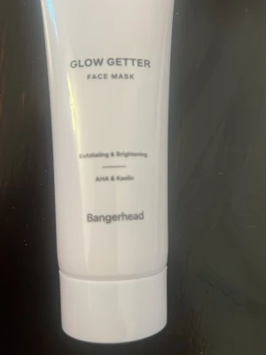 Glow Getter Face Mask från Bangerhead - Glow Getter Face Mask från Bangerhead är en exfolierande och lystergivande ansiktsmask med AHA och kaolin. Tuben är vit med svart text och rymmer 75 ml. Perfekt för dig som vill boosta huden med glow och fräsch känsla.