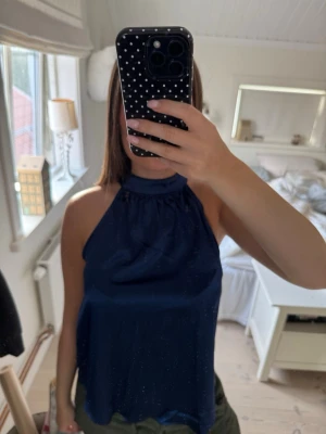 Mörkblå halterneck topp - Snygg mörkblå halterneck topp med hög krage och lös passform. Toppen är ärmlös och har ett glansigt material som ger en elegant känsla. Köpt från Shein och använt endast 1 gång! Fint skick alltså💗