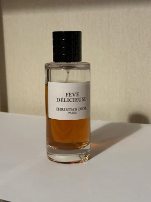 Fève Délicieuse parfym från Dior - Fève Délicieuse från Christian Dior är en lyxig parfym i en stilren, cylindrisk glasflaska med svart lock. Doften har en varm bärnstensfärgad vätska och etiketten är enkel och elegant med svart text. Perfekt för dig som gillar exklusiva dofter.
