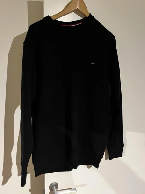 Svart långärmad tröja Tommy Hilfiger - Svart långärmad tröja från Tommy Hilfiger med diskret logga broderad på bröstet. Tröjan har rund halsringning och är tillverkad i ett mjukt material som passar perfekt till alla tillfällen. Vid funderingar skriv.✨