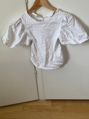Vit puffärm blus från Zara - Snygg vit blus från Zara med puffiga korta ärmar och rund halsringning. Tillverkad i ett mjukt bomullstyg som känns skönt mot huden. Perfekt att styla med jeans eller kjol för en trendig look.