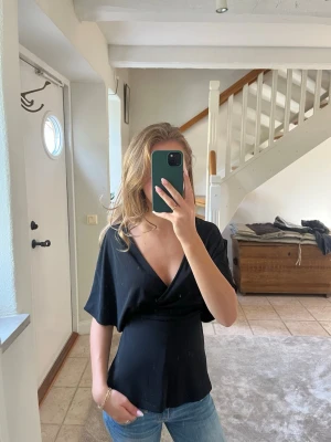 Svart blus  - Jättefin och elegant svart blus med snörning i ryggen och volangiga armar 