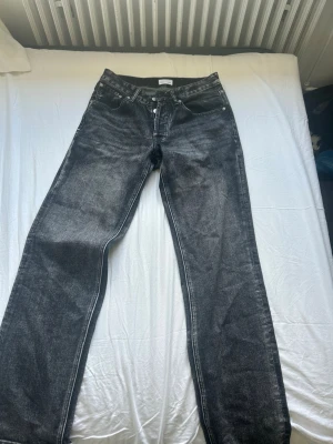 Svarta raka jeans med tvättad look - Säljer ett par svarta jeans med tvättad finish och raka ben ifrån BRAND ISLAND. OBS dom är lite uppklippta nere vid byxbenet