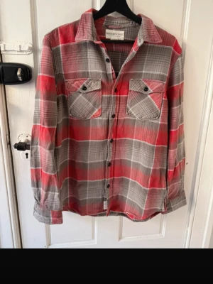 Denim & supply skjorta vintage  - Säljer en röd och grå rutig skjorta med långa ärmar och två bröstfickor med knappar. Skjortan har klassisk krage och knäppning framtill. Perfekt för en avslappnad och cool stil.