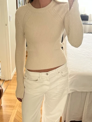 Beige ribbstickad tröja - Säljer en beige ribbstickad tröja med rund hals och långa ärmar. Tröjan har en figurnära passform och är tillverkad i ett mjukt, stretchigt material. Storlek XS men passar även mig som brukar ha S. 