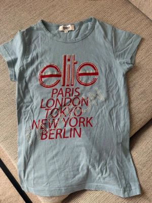 Ljusblå t-shirt från Elite Models - ljusblå t-shirt från Elite Models Fashion med korta ärmar. Köpt second hand i Milano! Skriv vid funderingar 🥰