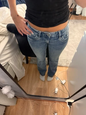 Low waist bootcut Jeans från Gina tricot - Säljer ett par blå jeans med låg midja och raka ben. Jeansen har klassisk femficksdesign och är tillverkade i denim med lätt tvättad look. Perfekta för en avslappnad och trendig stil.