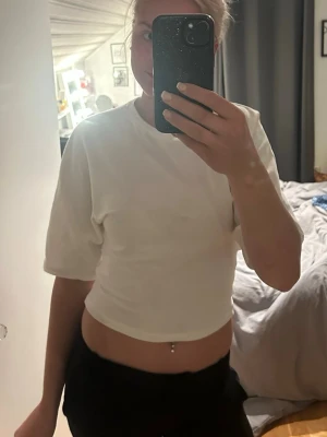 Vit croppad t-shirt med knyt - Säljer en vit croppad t-shirt i mjuk bomull. T-shirten har korta ärmar och kan stylas med knyt i midjan för en trendig look. Strl S från lager 157