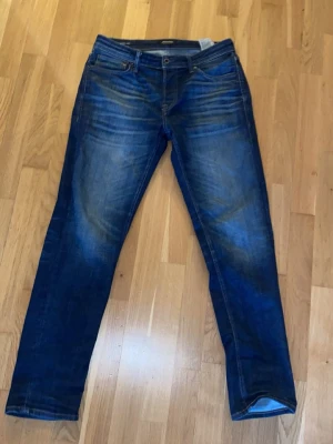 Blå tapered jeans från Jack & Jones - Snygga blå jeans från Jack & Jones i modellen Tapered/Mike ORD PRIS 899kr. Jeansen har klassisk femficksdesign, normalhög midja och avsmalnande ben. Materialet är slitstark denim med snygga slitningar och tvättade detaljer för en trendig look.