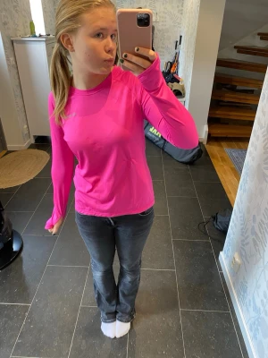 Långärmad rosa träningstopp - Säljer en långärmad träningstopp i stark rosa färg. Toppen har en enkel, klassisk design med rund halsringning och är tillverkad i ett mjukt, stretchigt material som känns bekvämt mot huden. Kan även stylas med jeans eller kjol för en färgklick i garderoben. 