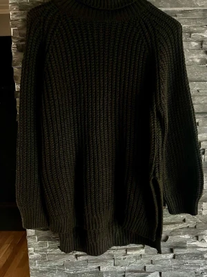Svart stickad polotröja - Säljer en svart stickad polotröja med grov ribbstickning. Tröjan har lång ärm, hög polokrage och avslappnad passform. Perfekt för kalla dagar och enkel att styla med jeans eller kjol. 