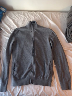 Grå Pier one full zip. - Pier one full zip, extremt clean med många fina detaljer som dubbel drag kedja, mörkblå på insidan av kragen. Den är inprincip nyskick. Modellen är 180 cm 75 kg och bär storlek M passar även storlek S skulle jag säga. Hör av dig om du har frågor!