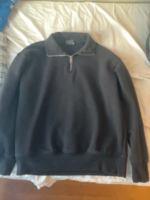 Svart half zip tröja - Säljer en svart half zip Tröja med en snygg silver dragkedja som  har långa ärmar, ribbade muddar och en relaxed passform. Materialet är super bekvämt och passar alla årstider . Enkel och clean design utan synligt märke, och man får höra massa komplimanger hör av dig om du har frågor.