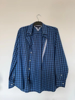 Blå långärmad skjorta i rutigt mönster - Snygg långärmad skjorta i blått/mörkblått rutmönster. Perfekt både öppen över en vit tshirt eller knäppt.