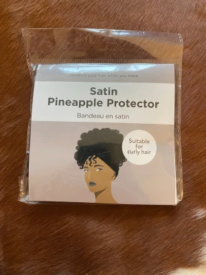 Satin Pineapple Protector hårband - Satin Pineapple Protector är ett brett satinband som skyddar lockigt hår och minskar friss under natten. Perfekt för att hålla ananasfrisyr på plats medan du sover. Passar dig med lockigt hår och används på torrt hår. Aldrig använd. Tvättas med liknande färger.