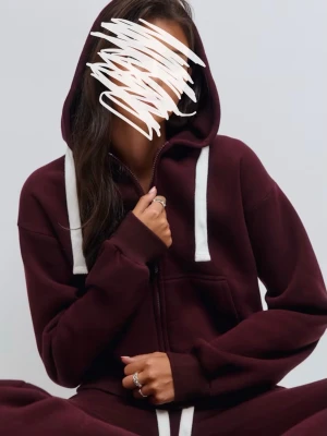 Vinröd hoodie med dragkedja och huva - Mysig vinröd hoodie med dragkedja framtill och stora vita snören i huvan. Hoodien har känguruficka och ribbade muddar vid ärmslut och nederkant. Perfekt för chill dagar och enkel att matcha med andra plagg.