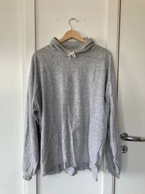 Grå vintage hoodie från Expand - Ljusgrå hoodie från Expand med huva och dragsko. Tillverkad i tunt material. Klassisk passform med långa ärmar och enkel design utan tryck eller fickor. Perfekt för en chill och avslappnad stil.