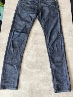 Replay Willbi - Säljer ett par mörkblå jeans med raka ben och klassisk femficksmodell. Jeansen har kontrastsömmar och detaljerade bakfickor med vita sömmar. Perfekta för en avslappnad och stilren look.