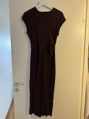 Mörkbrun klänning från Mango - En stilren mörkbrun långklänning med rund halsringning och korta ärmar. Perfekt för dig som gillar minimalistisk design och mjuka material.