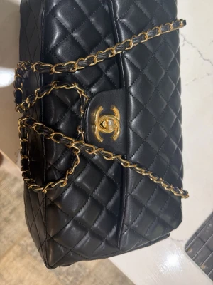 Svart elegant väska  - Snygg svart quiltad handväska från Zara” med klassiskt mönster och guldfärgad kedja. Väskan har ikoniskt CC-spänne i guld och axelrem i kedja med läderdetaljer. Perfekt för dig som vill ha en tidlös och lyxig accessoar.