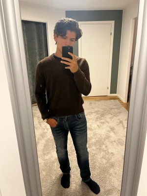 Brun stickad tröja Polo Ralph Lauren - Mörkbrun stickad tröja från Polo Ralph Lauren med rund halsringning och diskret röd logga broderad på bröstet. Tröjan har långa ärmar och ribbade muddar vid ärmslut och nederkant. Materialet är i marino ull mjukt och lite luddigt, perfekt för kyligare dagar. Tveka inte på att skriva vid intresse🌟😊