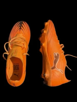 Orangea Puma fotbollsskor - Säljer ett par grymma orangea fotbollsskor från Puma med vita detaljer och klassisk logga på sidan. Skorna har snörning och dobbar för optimalt grepp på planen. Lätta och smidiga i syntetmaterial, perfekta för snabba vändningar och explosiv fart.