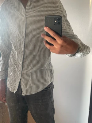These glory days skjorta  - Snygg skjorta med smala vertikala ränder i vitt och grått. Klassisk krage, långa ärmar och knäppning framtill. Perfekt till jeans eller chinos för en clean look.