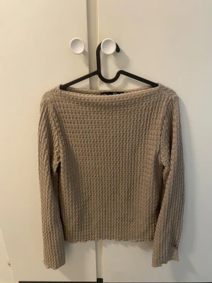 Beige ribbad långärmad topp - Säljer en beige långärmad topp med ribbad struktur och rund hals. Toppen har en avslappnad passform och är tillverkad i ett mjukt material som känns skönt mot huden. Perfekt att styla med jeans eller kjol för en enkel och snygg look.