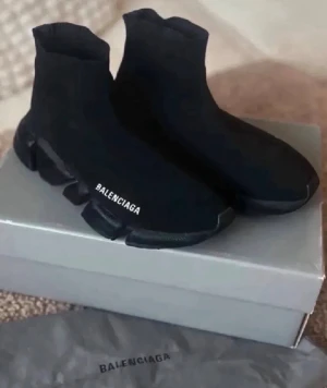 Svarta Balenciaga Speed sneakers - Säljer ett par svarta Balenciaga Speed sneakers med stickad ovandel och tjock, platt sula. Skorna har en strumpliknande passform och Balenciaga-logga på sidan. Perfekta för dig som gillar en modern och sportig look.