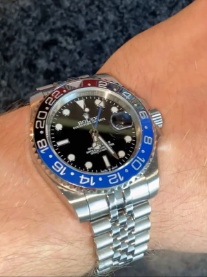 GMT-Master II Batgirl - Snygg Rolx GMT-Master II Batgirl med svart och blå vridring, svart urtavla och jubilee-länk i rostfritt stål. Klockan är en superclone som har varit i min ägo i cirka 2 år. Fint skick. Kom med förslag, inga skambud. Jag gör en intressekoll, säljer endast vid ett bra förslag.