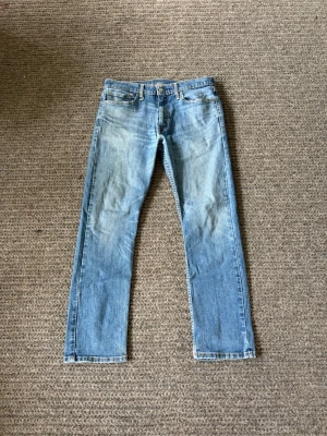 Ljusblå raka jeans - Säljer ett par ljusblå jeans med rak passform och klassisk femficksdesign. Jeansen har slitna detaljer och är tillverkade i denim med en snygg tvätt. Perfekta för en avslappnad och trendig look.