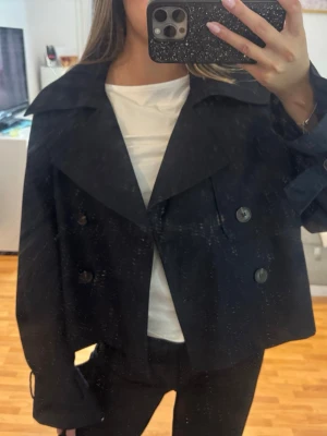 Kort trenchcoat - Superfin trenchcoat som är oanvänd, fint skick, som ny! Färgen är marinblå, nästintill svart!