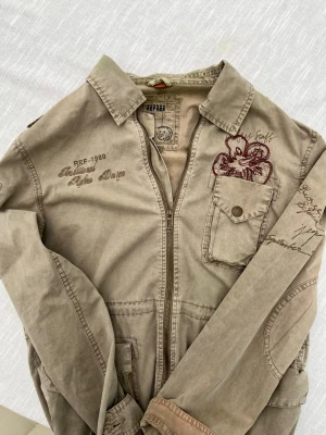 *Unik Overshirt* - En mycket unik Overshirt från REFREE. Med fina detaljer och dess sällsynta design är detta ett mycket eftertraktat plagg nu till hösten! Storleken är följande: M. Öppen för prisförslag vid snabb affär. Hör av dig vid frågor!