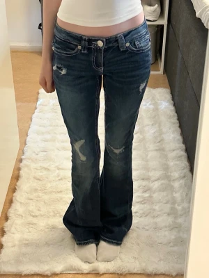 Lågmidjade jeans - Mörkblå flare jeans med detaljer på bakfickorna och hål. Aldrig använda och i nyskick! Katt finns i hemmet