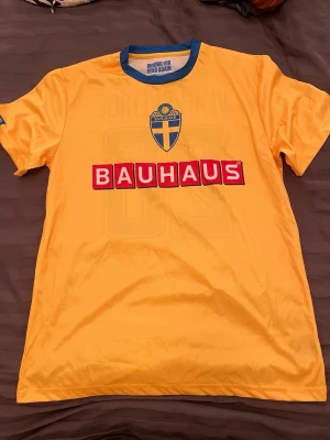 Sverige Supportertröja / Matchtröja Bauhaus - Storlek XL - Gul och blå svensk supportertröja i skönt funktionsmaterial. Sverigesköld och Bauhaus-tryck framtill samt "Vi är Sverige 26" och "För gul & blå står vi upp" på baksidan. Perfekt till mästerskap, landskamper eller träning!  Skick: Mycket fint skick, trycken är fräscha och tyget är helt och rent.  Färg: Gul med blå detaljer  Tryck: Sverige-sköld, Bauhaus, "Vi är Sverige 26"  Storlek: XL (Extra Large)  Material: Funktionspolyester ✨ Kika gärna på mina andra varor på sidan! Jag säljer just nu av en 