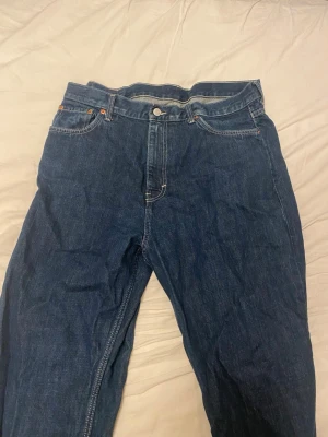 Mörkblå raka jeans med fem fickor - Säljer ett par klassiska weekday galaxy mörkblå jeans med rak passform. Perfekta för en avslappnad och tidlös look. Materialet är kraftig denim i bomull. Storleken är W34 och L32. Hör gärna av er vid frågor