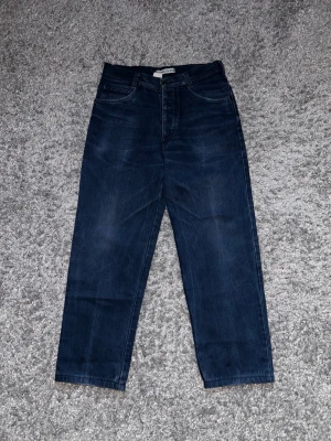 Mörkblå raka jeans från Stone Island - Säljer ett par mörkblå jeans med rak passform och hög midja. Jeansen har klassiska fem fickor och en snygg patch på ena bakfickan. Materialet är kraftigt denim som ger en tidlös look. Perfekta till sneakers eller boots. Passar typ Xs/S