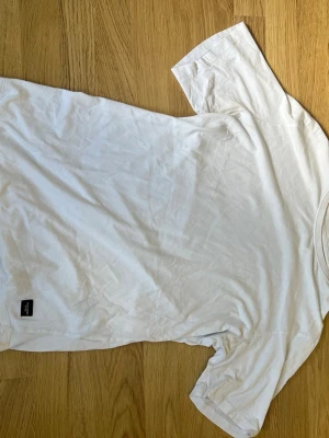 Vit t-shirt från Jack & Jones - Klassisk vit t-shirt från Jack & Jones Essentials i mjuk bomull. Enkel design med rund hals och korta ärmar, perfekt till jeans eller shorts. Skön passform och lätt att matcha med allt i garderoben.