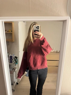 Vinröd hoodie med ficka framtill - Säljer en vinröd hoodie med klassisk känguruficka och huva. Hoodien har en avslappnad passform och ribbade muddar vid ärmar och nederkant. Perfekt för en chill och bekväm stil. Materialet känns mjukt och skönt mot huden.